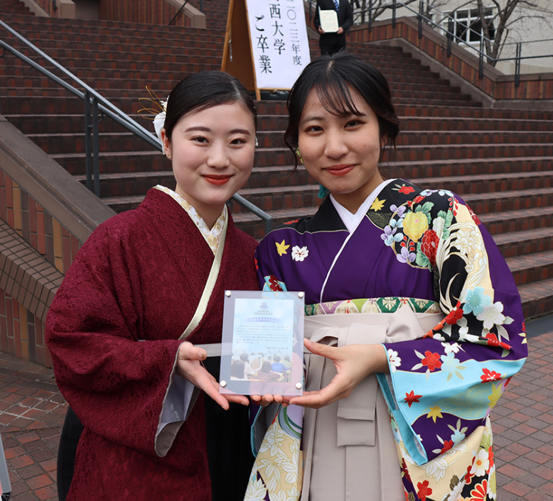フォトスタンドを手に喜ぶ卒業生2名